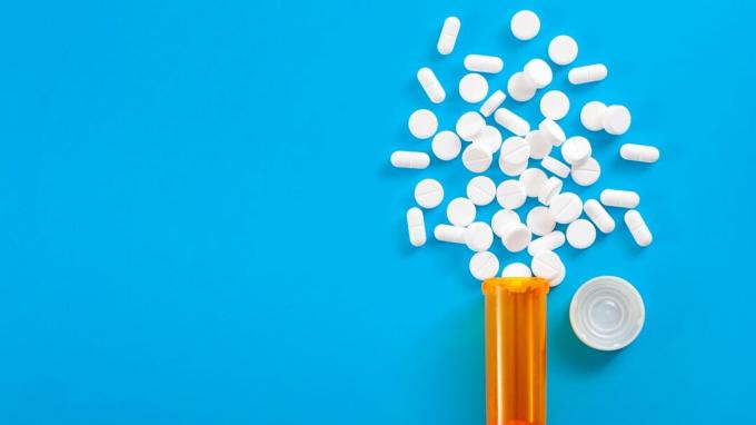 Koncept medicine, opioidnih lijekova protiv bolova i lijekova na recept s pogledom odozgo narančastom bočicom tableta za oksikodon i hidrokodon prosipane su na plavoj pozadini s prostorom za kopiranje